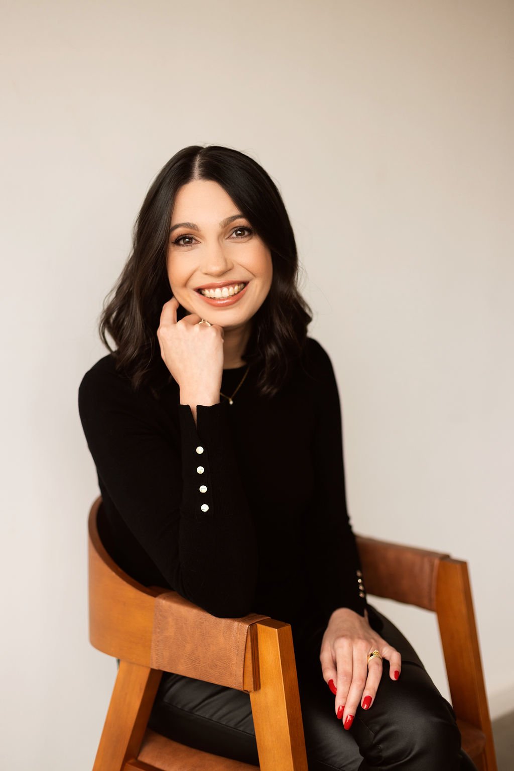 Dra. Laiza Tabisz sentada em uma cadeira, sorrindo para a câmera